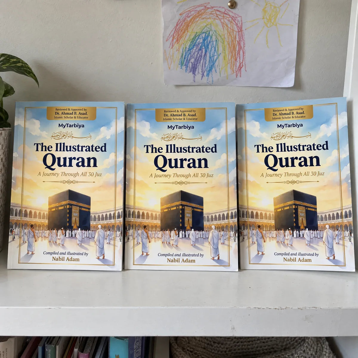 Three copies of The Illustrated Quran on a shelf
